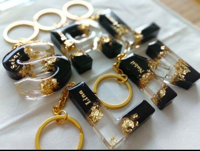 Black and gold keychains with names engraved on a white surface