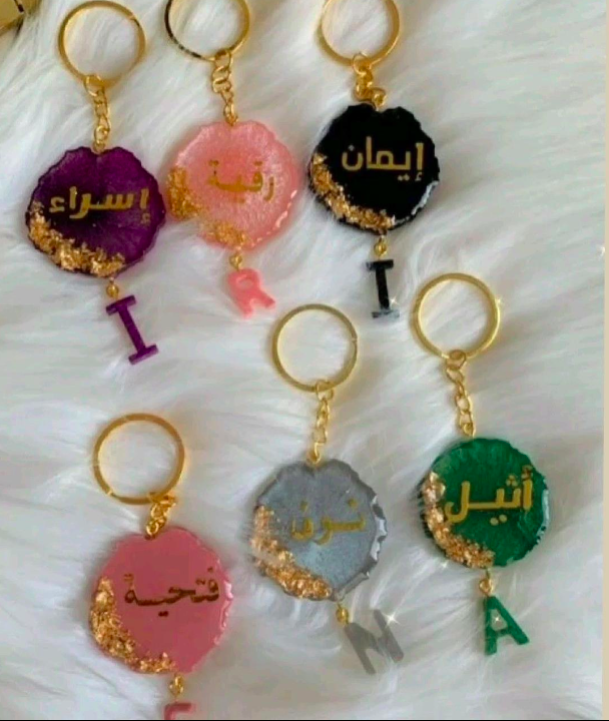 Collection of colorful keychains with Arabic text on a white background