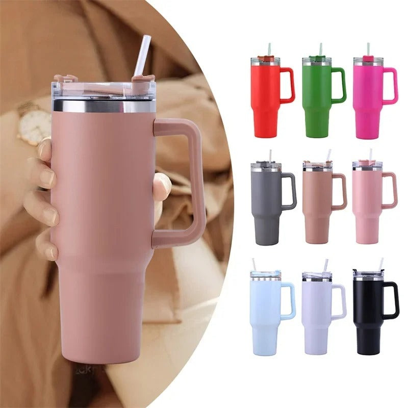 Pink insulated mug with handle held by a person, surrounded by other colored mugs on a white background.