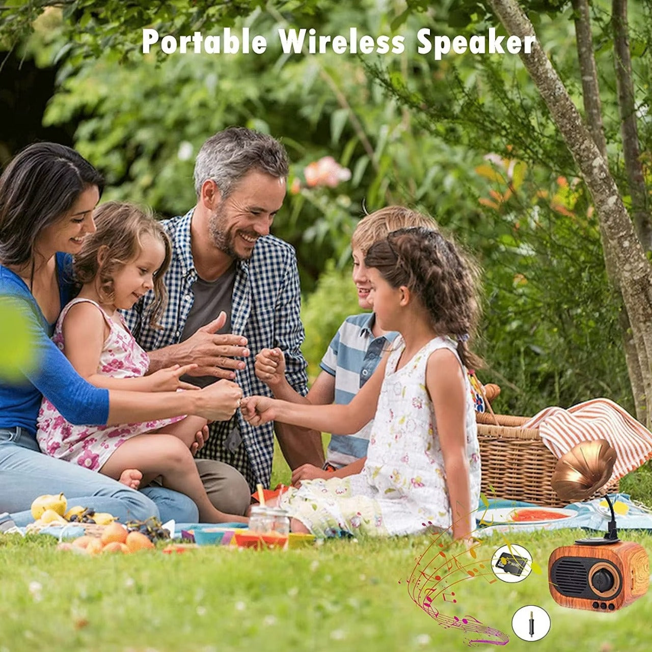Family sitting on a blanket outdoors with a portable wireless speaker in the foreground.