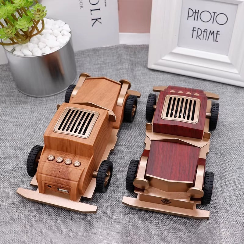 Two wooden toy cars on a textured surface with a plant and photo frame in the background.