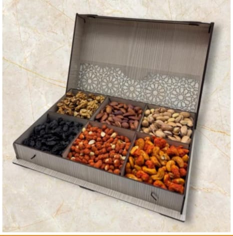 Open box of assorted dried fruits on a light marble background