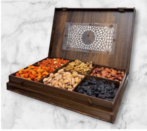 Wooden box with compartments filled with various dried fruits on a marble surface
