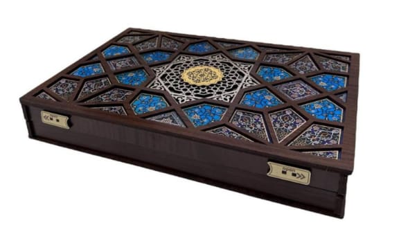 Decorative wooden box with geometric patterns and blue stones on a white background