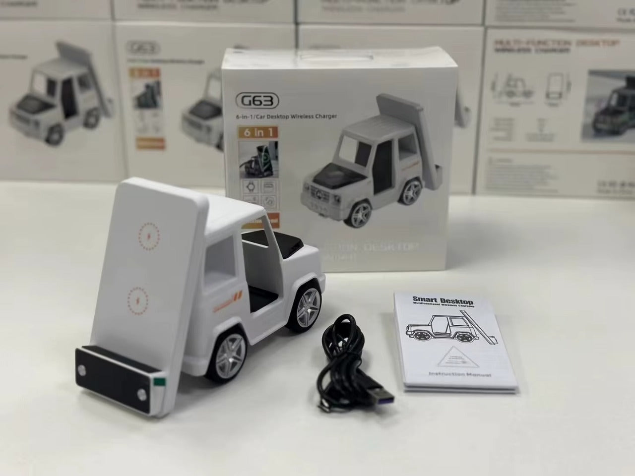 White toy truck with charging stand, cable, and manual on a white surface with product packaging in the background.