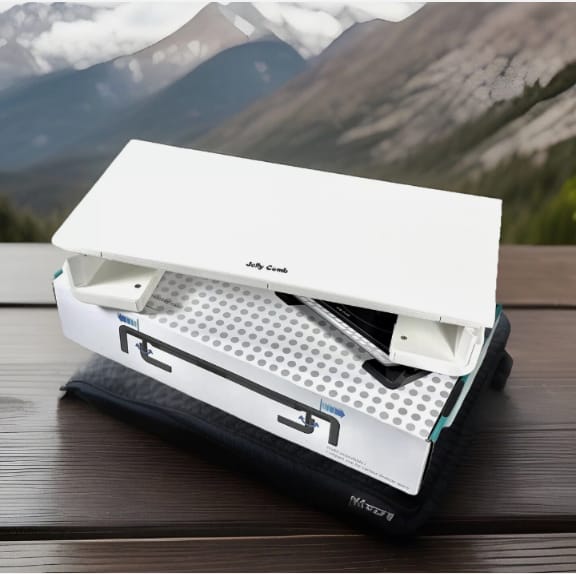 Portable solar oven on a wooden surface with mountains in the background