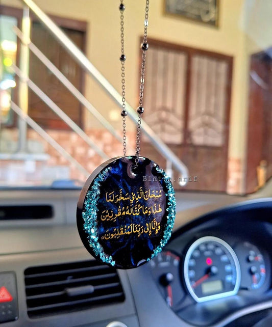 Decorative hanging car accessory with Arabic text inside a car.