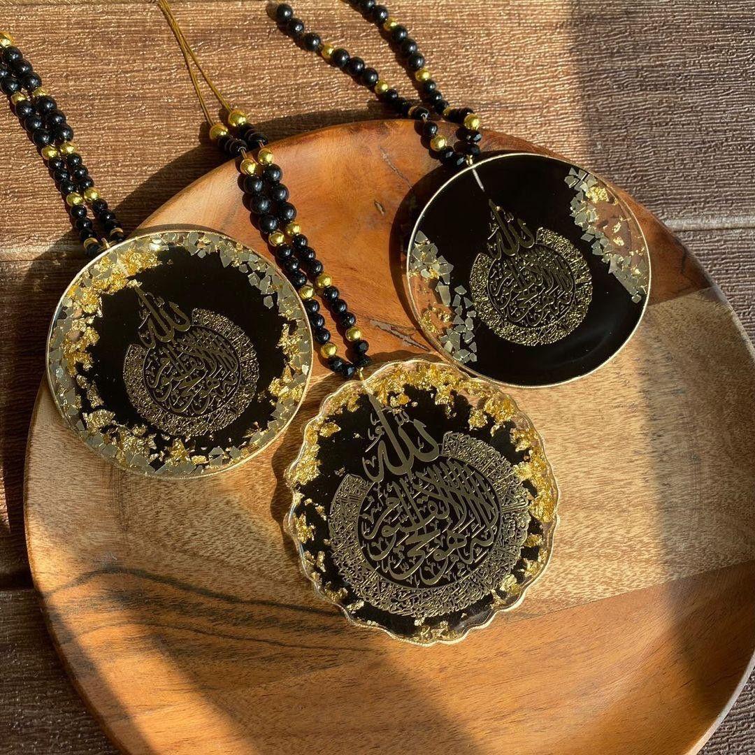 Three black and gold necklaces with intricate designs on a wooden surface