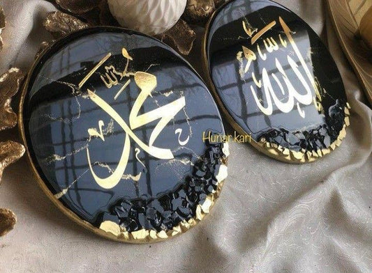 Two decorative items with gold Arabic calligraphy on a dark background, placed on a textured surface.