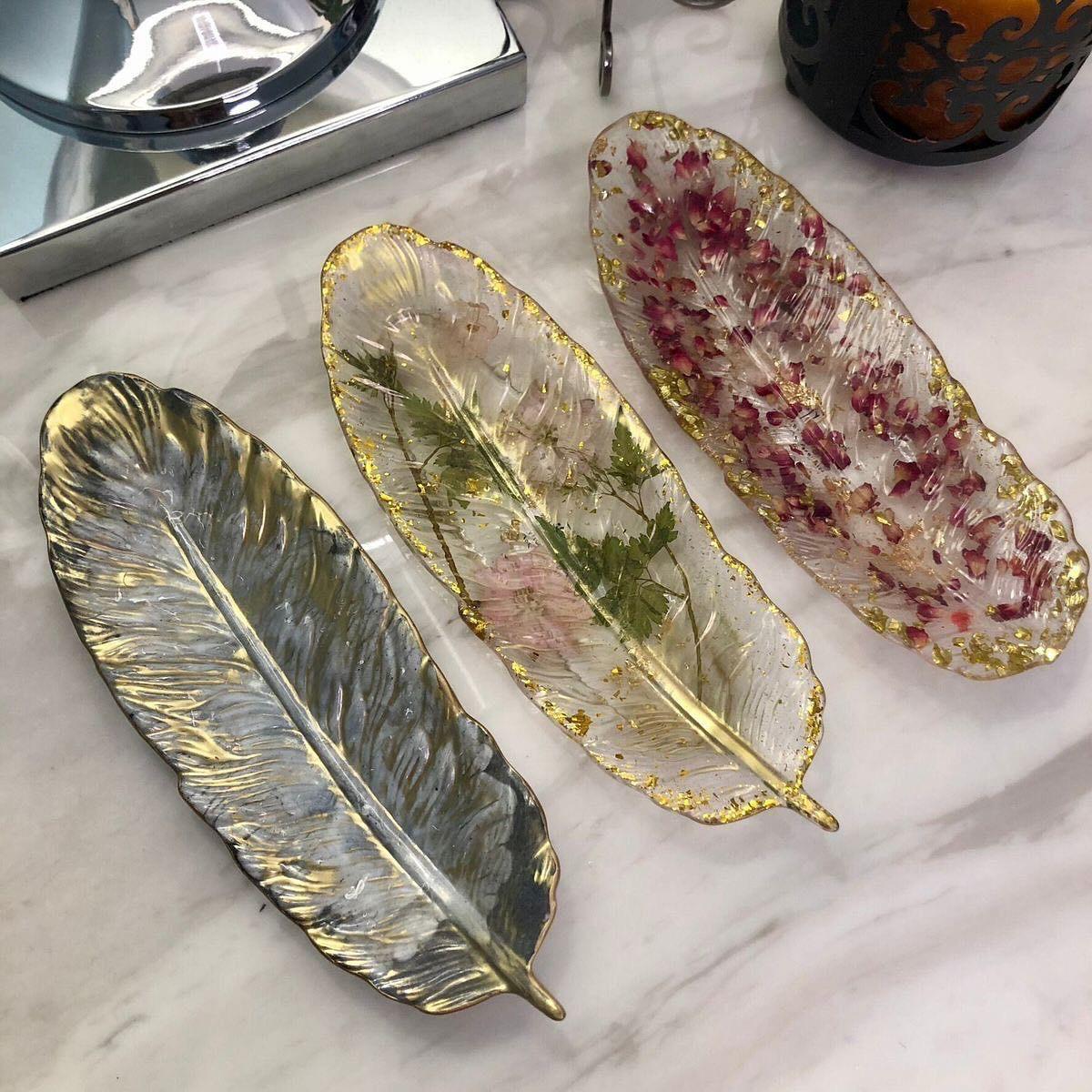 Three leaf-shaped decorative plates with gold edges on a marble surface.