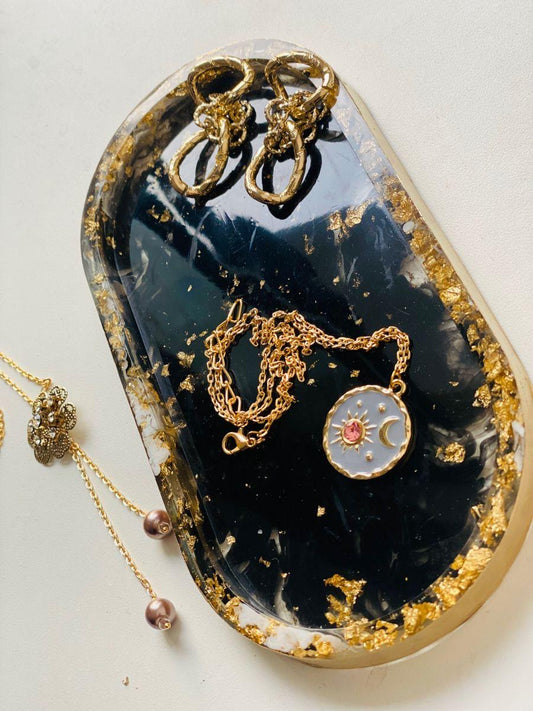 Jewelry set including earrings and necklaces on a decorative black and gold stone.
