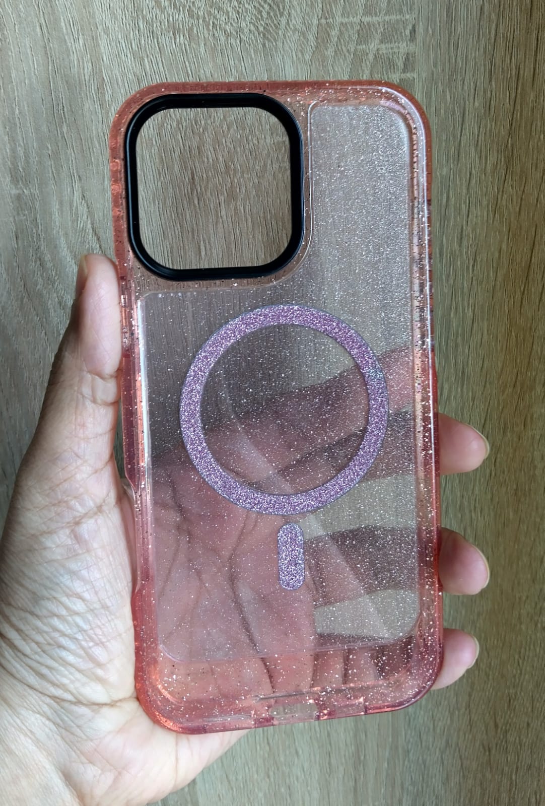 Phone case with a clear design held by a hand on a wooden surface