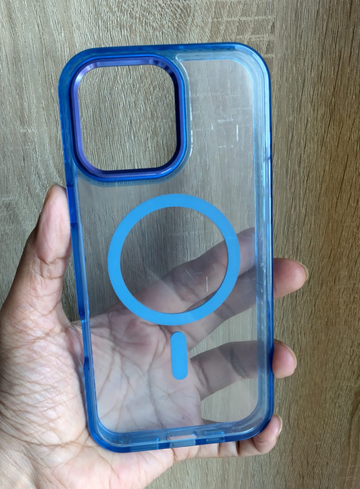 Blue phone case held by a hand on a wooden surface