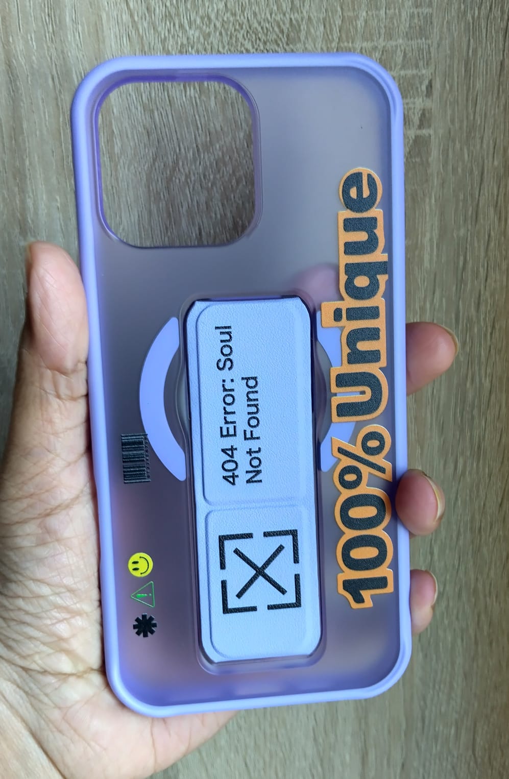 Phone case with text and design held by a hand on a wooden surface