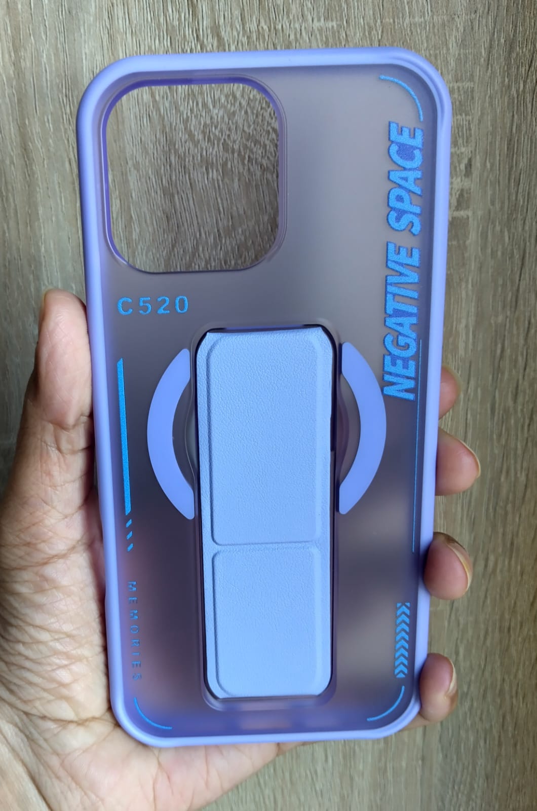 Phone case with 'Negative Space' branding held by a hand on a wooden surface