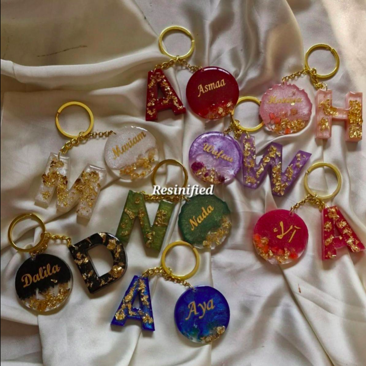 Collection of colorful resin keychains with names on a white fabric background