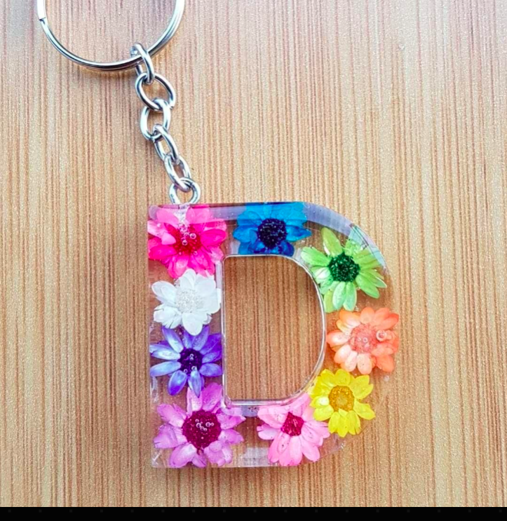 Keychain with colorful flowers shaped like the letter 'D' on a wooden surface