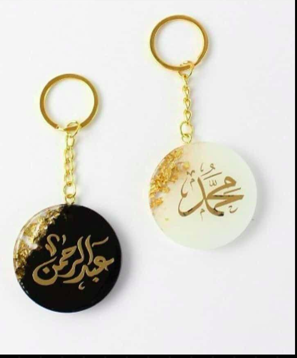 Two keychains with gold Arabic calligraphy on a white background