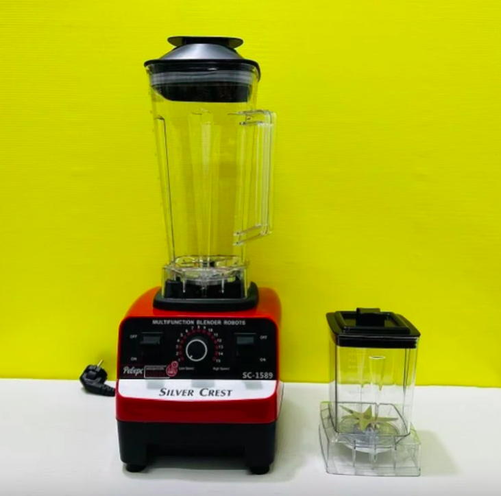 Blender with fruits, juice glasses, and a basket of fruits on a white background