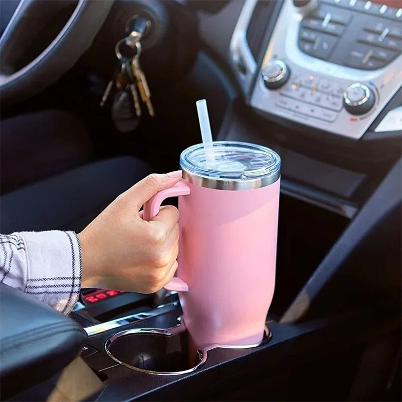 Person holding a pink insulated cup with a straw in a car.