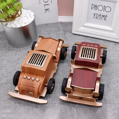 Two wooden toy cars on a textured surface with a plant and photo frame in the background.