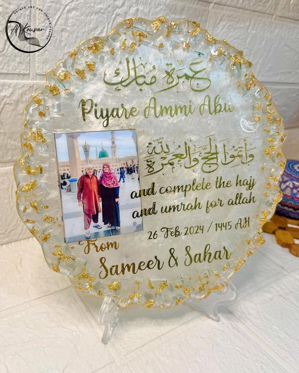 Decorative plaque with gold text and a photo of two people, placed on a textured surface.