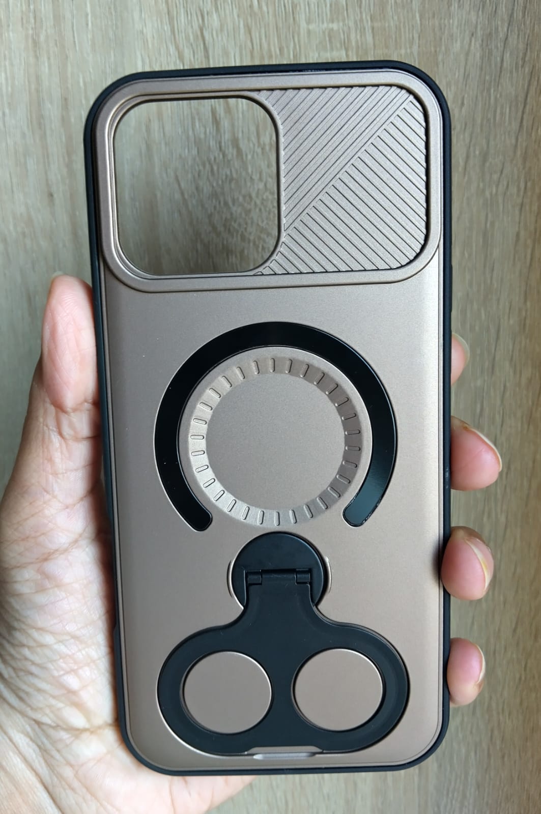 Phone case with ring holder held by a hand on a wooden surface